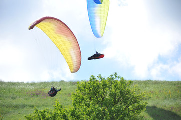 Paraglider flying on colored parachute in blue clear sky at a bright sunny summer day. Active...
