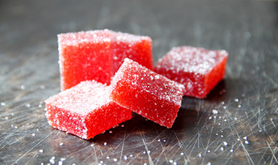 Strawberry pate de fruit (jelly, marmalade, fruit candy) covered with sugar on a dark background, back view