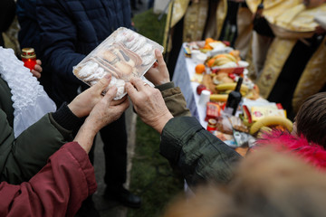 Shallow depth of field (selective focus) image with the hands of people holding sweets during a Christian Orthodox ceremony called Memory Eternal to honor the dead.