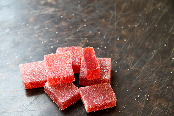 Strawberry pate de fruit (jelly, marmalade, fruit candy) covered with sugar on a dark background,...