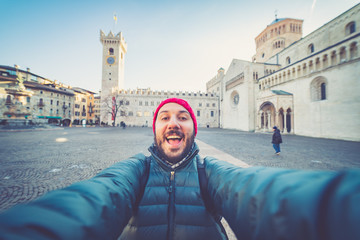 Fototapeta premium happy man tourist take selfie photo in Piazza del Duomo central square in Trento. Trento is a city on the Adige River in Trentino Alto Adige Sudtirol in Italy.