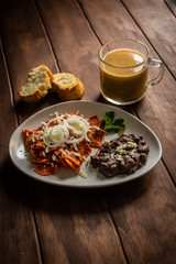 Plato de Chilaquiles y frijoles caseros con crema y queso cotija cafe y jugo desayuno tradicional mexicano