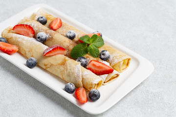 Healthy summer breakfast. Pancakes with blueberries, fresh strawberries and mint. Delicious Tasty Homemade crepes. 