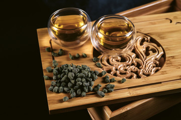Chinese tea ceremony. Cups at tea board with hot green tea, milky oolong ginseng on black background