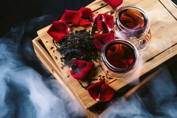 Obraz na płótnie Canvas Chinese tea ceremony. Still life with traditional Asian Yunnan black tea, red tea in classic cups and rose petals as symbol of flower flavor of drink