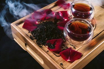 Chinese tea ceremony. Still life with traditional Asian Yunnan black tea, red tea in classic cups and rose petals as symbol of flower flavor of drink