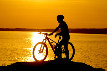 Fototapeta na wymiar silhouette of a cyclist with sunset background. Orange sky, hobby, healthy habbits.