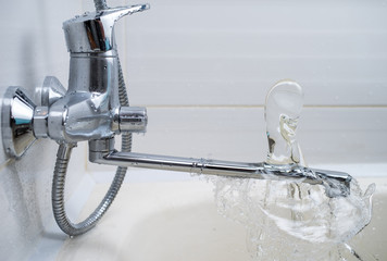 Stream of water pouring onto the faucet in the bathroom. Selective focus.