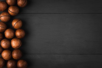 Macadamia nuts on a dark wooden background on the side