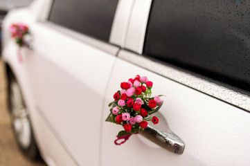 wedding car with beautiful flower decorations. White car, red flowers, wedding day, selective focus, closeup