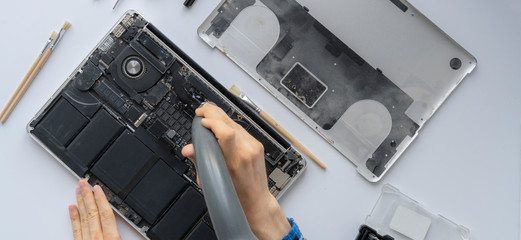 man's hands working in computer service and remove dust from the personal laptop