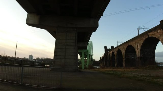 Driving under arched green steel bridge & railway crossing urban metal regeneration overpass.