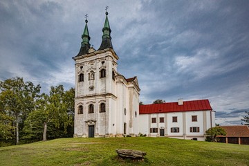 Naklejka premium Krahulci / Czech Republic - September 27 2019: View of a baroque Church of John of Nepomuk, a white building from 18th century standing on a green hill on a sunny day with blue sky and clouds.