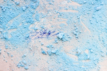 Close up of crumbled (crushed) small blue meringues, light grey stone background.