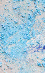 Close up of crumbled (crushed) small blue meringues, light grey stone background.