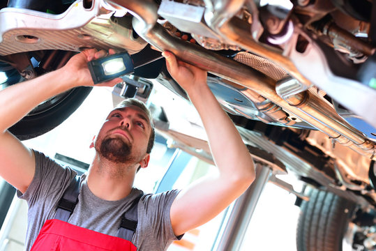 Auto Mechanic Repairs Vehicle In A Workshop - Checking Brakes For Safety