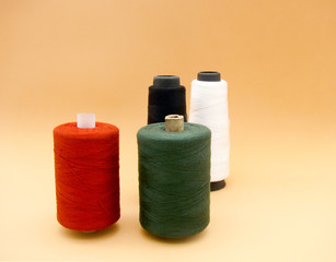 four reels of colored thread on a beige background