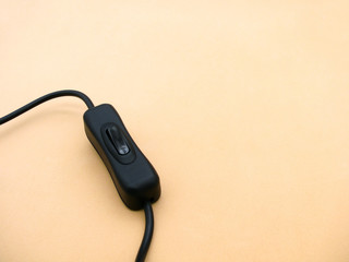black electro-switch on a wire on a beige background. toggle