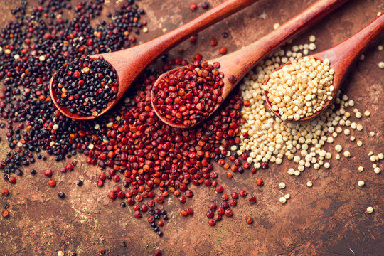 Red, black and white quinoa grains in a wooden spoon. Healthy food background. Seeds of white, red and black quinoa - Chenopodium quinoa. Vegetarian food