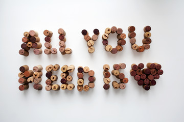 Wine corks ALL YOU NEED IS LOVE text with heart shape isolated on white background
