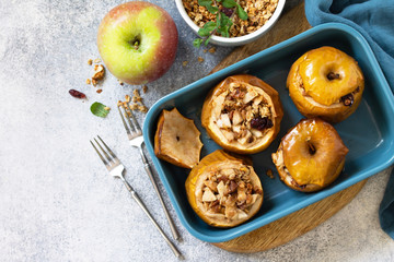 Diet menu. Healthy dessert. Baked apples with walnuts, honey and granola on slate, stone or concrete background. Top view flat lay background. Copy space.