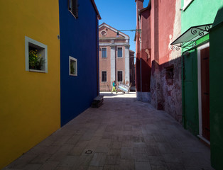 Fototapeta na wymiar Morning on the island of Burano. Colored facades. The streets of the old city of Venice. Bright sun. The beauty of the ancient city. Italy.