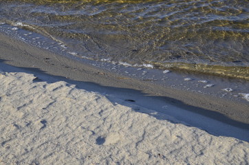 Sandy beach. Waves on the water. Evening