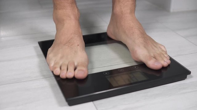 Mann wiegt sich auf einer Personenwaage 