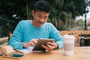 Asian man studying in coffee shop.