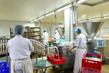 Obraz premium Arbeiter in einer Fleischerei - Herstellung von Würsten in einer Fabrik für Lebensmittel // worker in a butchery - production of sausages in a food factory