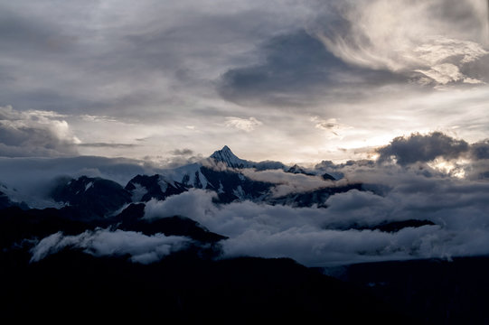 Snow capped peak of sacred mountain Kawagarbo (Khawa Karpo, Kawadgarbo, Khawakarpo, Moirig Kawagarbo, Kawa Karpo or Kha-Kar-Po) emerges above the clouds under a majestic sky from a distance