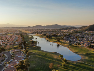 Aerial view of golf course surrounded by town houses and luxury villas during sunset time....