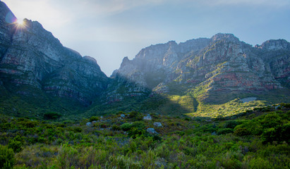 Sunlight popping over mounatins at sunrise in nature in Camps Bay.