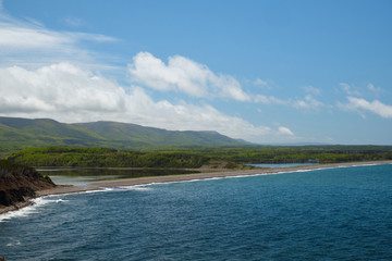 View on a lagoon, coastline of Nova Scotia and green forest. Blue cloudy sky and mountains.