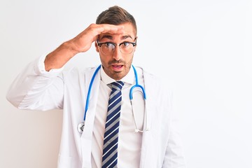 Young handsome doctor man wearing stethoscope over isolated background very happy and smiling looking far away with hand over head. Searching concept.