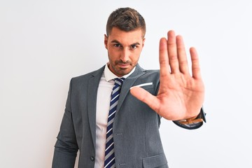 Young handsome business man wearing suit and tie over isolated background doing stop sing with palm of the hand. Warning expression with negative and serious gesture on the face.
