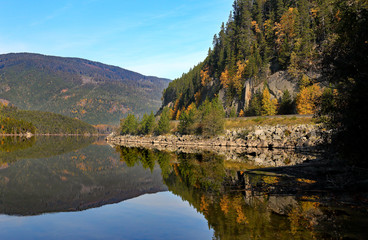 Lake with autumn forest and mountains reflected in the water