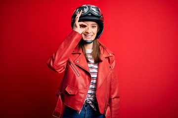 Young beautiful brunette motocyclist woman wearing motorcycle helmet and red jacket doing ok...