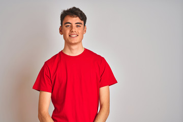 Teenager boy wearing red t-shirt over white isolated background looking away to side with smile on face, natural expression. Laughing confident.