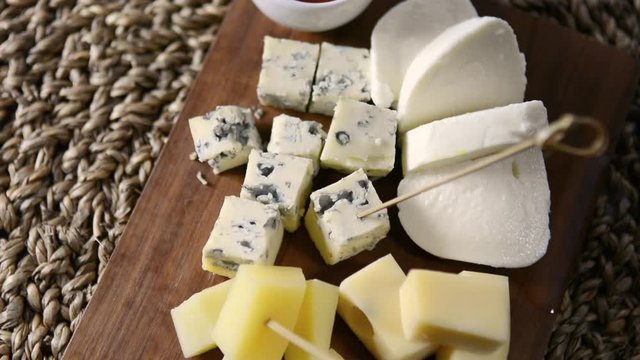 Cheese plate. Wooden Board with several types of cheese and honey. Movement.
