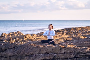 Young beautiful sportwoman smiling happy practicing yoga. Coach with smile on face teaching prayer pose at the beach