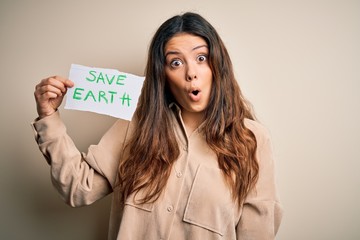 Young beautiful woman holding paper asking for save earth and enviroment conservation scared in...