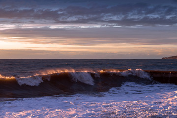 Sea sunset. Waves roll on the shore. The violence of the elements. Sea foam.