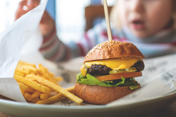 child eats a mini Burger and fries. children's menu in the cafe