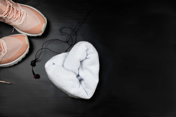 Woman sneakers, earphones and towel heart. Fitness concept.