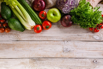 Border of tasty and healthy vegetables and fruits on a light rustic background.Top view. Copy space