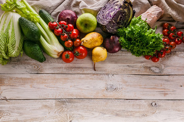 Top view border of tasty and healthy vegetables and fruits on a light rustic background. Copy space