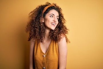 Young beautiful woman with curly hair over yellow background