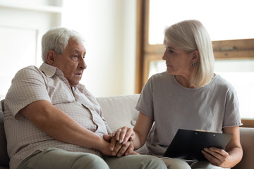Middle-aged nurse visit elderly male patient at home