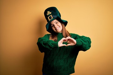 Young beautiful brunette woman wearing green hat on st patricks day celebration smiling in love...